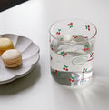 Three glasses with decorative patterns, including two with floral designs and one with a striped design, displayed on a table with a blurred background.