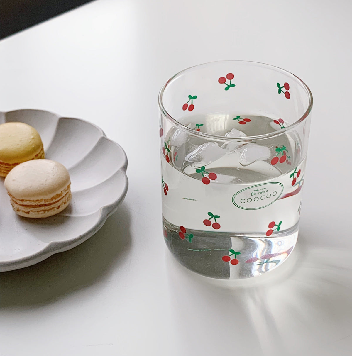 Three glasses with decorative patterns, including two with floral designs and one with a striped design, displayed on a table with a blurred background.