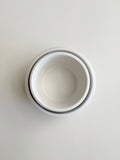 Three nested white ceramic bowls stacked vertically, viewed from directly above on a light gray background.
