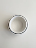Three nested white ceramic bowls stacked vertically, viewed from directly above on a light gray background.