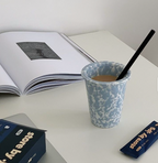 Cup with a straw on a table next to an open book and a box.