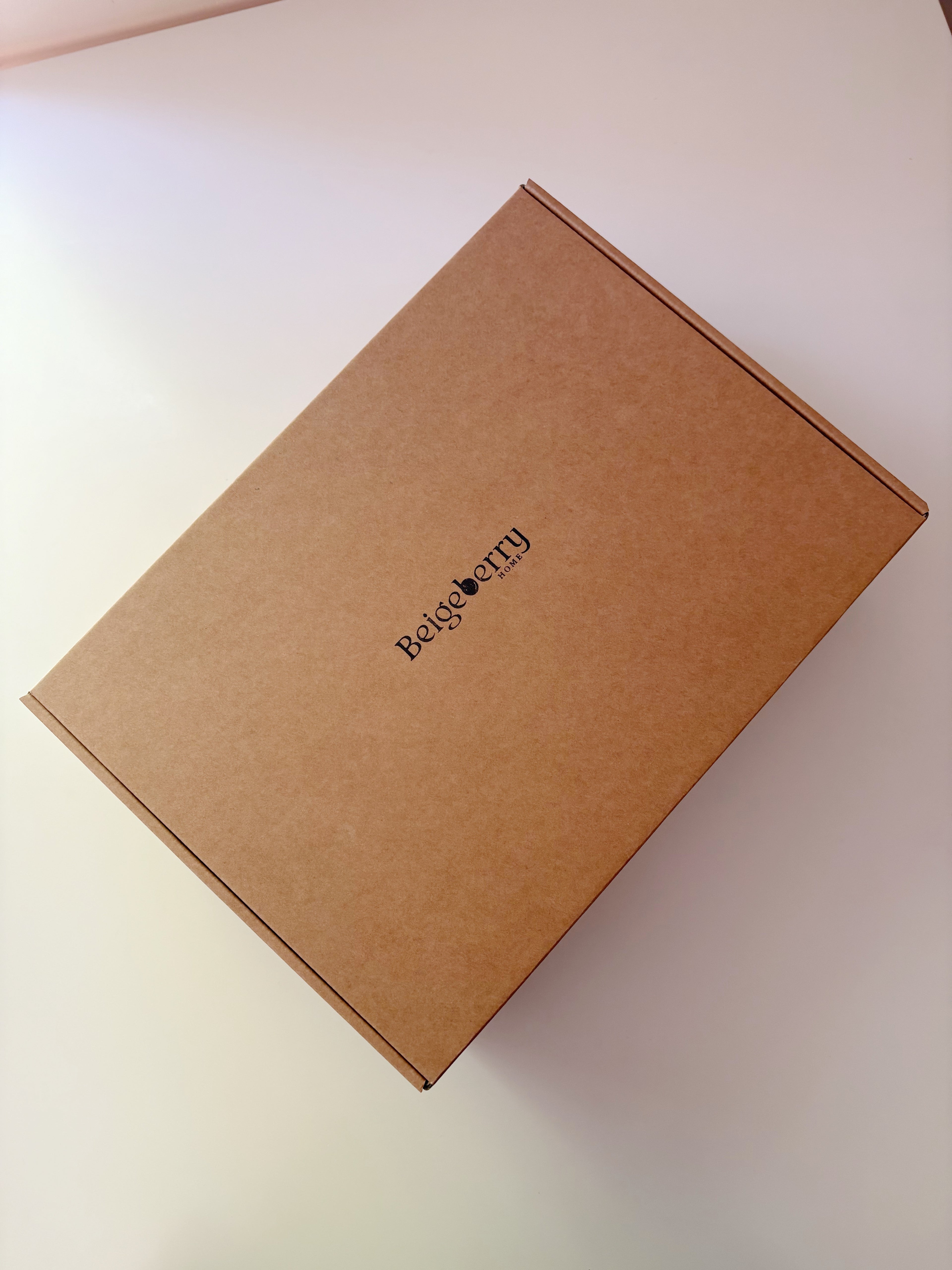 A brown kraft paper box with the brand name 'Blossberry' printed in black near the center, photographed on a plain off-white surface.