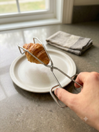 kitchen tong holding croissant 